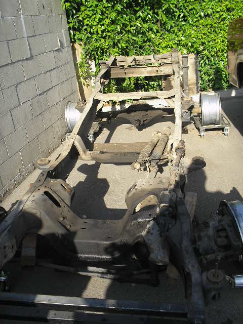 1986 Ford Bronco - Frame and suspension parts are laid out for a vehicle project.