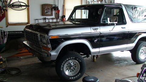 1979 Ford Bronco - A black and silver Ford Bronco is parked inside a garage with tools and a bicycle visible.
