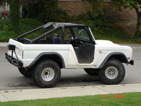 1968 Ford Bronco - 1968 Ford Bronco parked on a street, showing its side profile and off-road modifications.