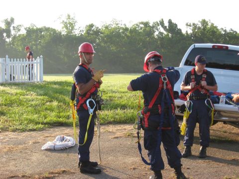 2006 Ford F-150 - Rescue personnel in harnesses and hard hats prepare near a white pickup truck, with ropes coiled on the ground.