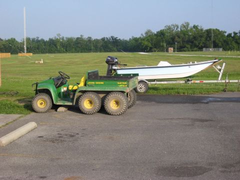2006 Ford F-150 - A John Deere Gator utility vehicle is parked beside a boat on a trailer in an open field.