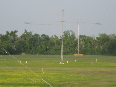 2006 Ford F-150 - Two tall radio towers with circular antennas stand in a wide, grassy field under a hazy sky.