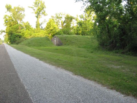 2006 Ford F-150 - A concrete structure is partially visible, built into a grassy embankment beside a paved road, surrounded by trees.