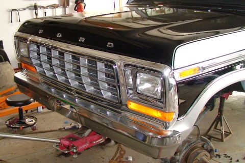 1979 Ford Bronco - The front grille and headlights of a classic Ford Bronco are visible, with the vehicle supported by jack stands.