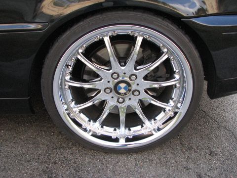 2002 BMW 3 Series - Close-up of a chrome BMW wheel, the brand's iconic logo, on a black vehicle.