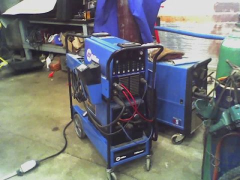 1992 Ford Bronco - Industrial welding equipment is set up in a cluttered garage or workshop environment.
