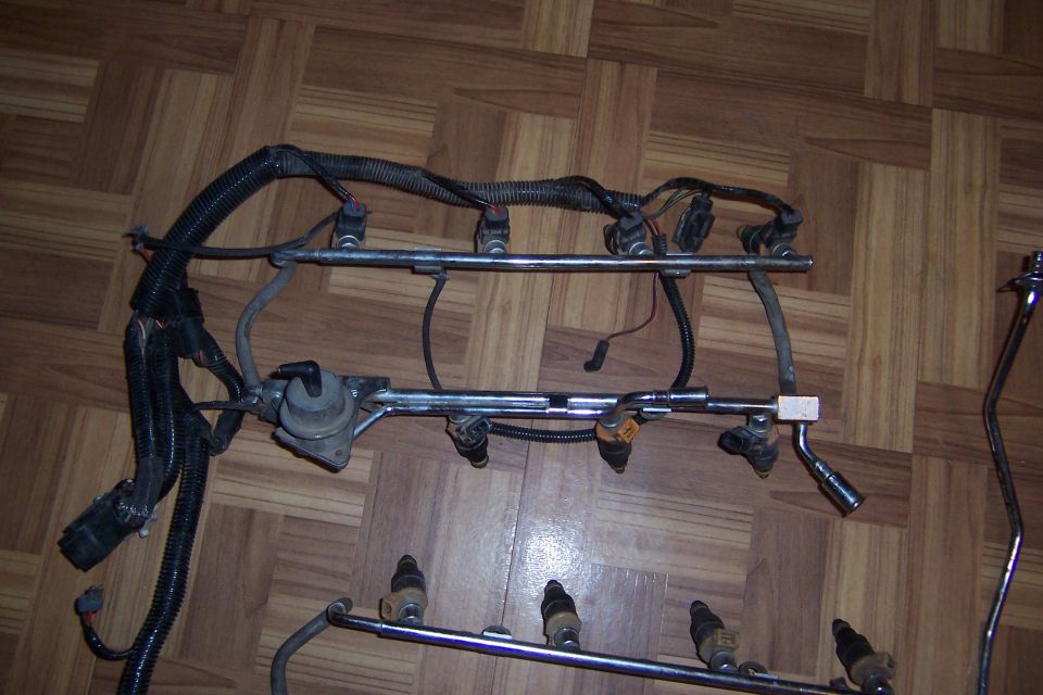 Fuel injector rail assembly with injectors and wiring harness on a wooden floor