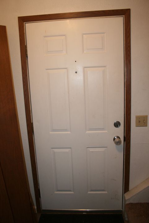 2003 Jeep TJ - A white interior door with a wooden frame is shown, with a light switch visible on the right wall.