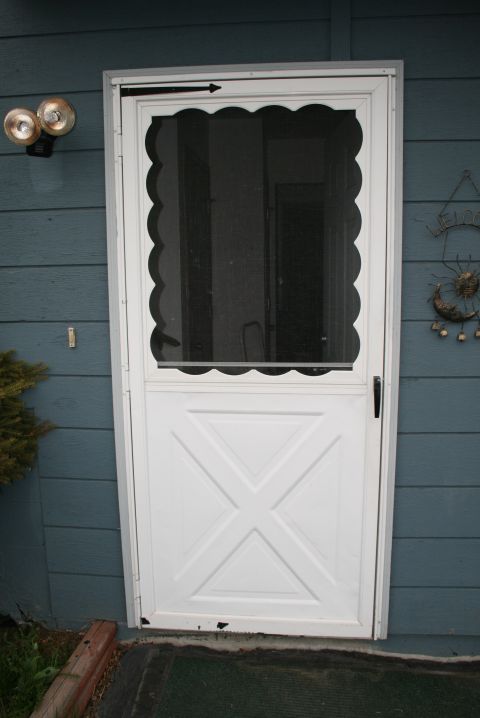 2003 Jeep TJ - A white screen door with decorative elements is shown on a blue house exterior wall.