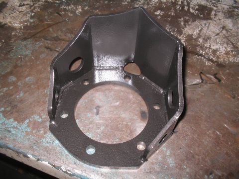 1979 Ford Bronco - A custom metal bracket, likely for a vehicle modification, is shown up close on a workbench.