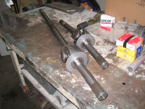 1979 Ford Bronco - Axle shafts and U-joints are laid out on a workbench with parts boxes.