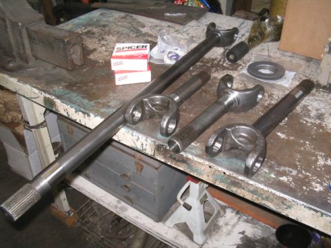 1979 Ford Bronco - Several driveshafts and yokes are laid out on a workbench, with two boxes of Spicer parts visible.