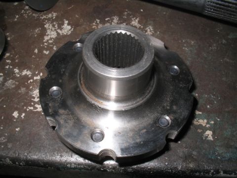 1979 Ford Bronco - A close-up view of a metal automotive part, likely a wheel hub, resting on a worn surface.