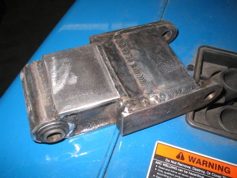 1979 Ford Bronco - A close-up of a custom-welded metal bracket, likely a vehicle part, with a warning label in the foreground.