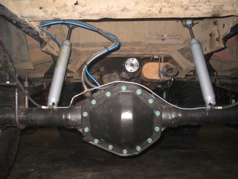 1979 Ford Bronco - Underside view of a vehicle's rear axle, leaf springs, and dual shock absorbers, with visible brake lines and air suspension components.