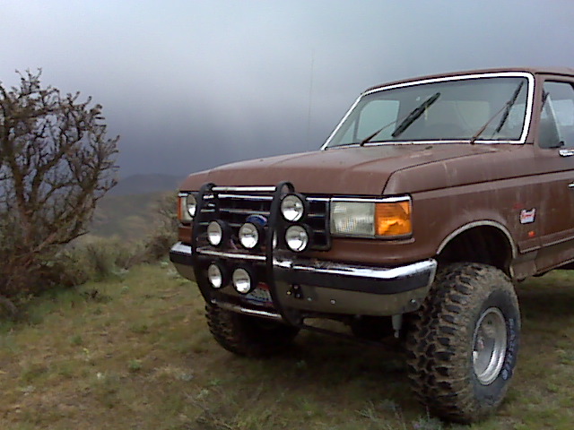 Brown Ford truck with brush guard and off-road tires, viewed from the front-right