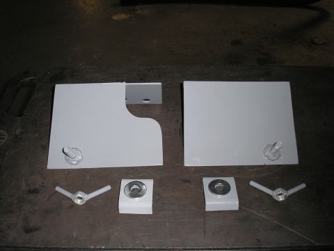1995 Ford Bronco - Two gray metal hi lift mount brackets and four fasteners are laid out on a dark surface.