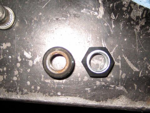 1996 Ford Bronco - Comparison of a used, rusty nut next to a new, black hexagonal nut on a workbench.