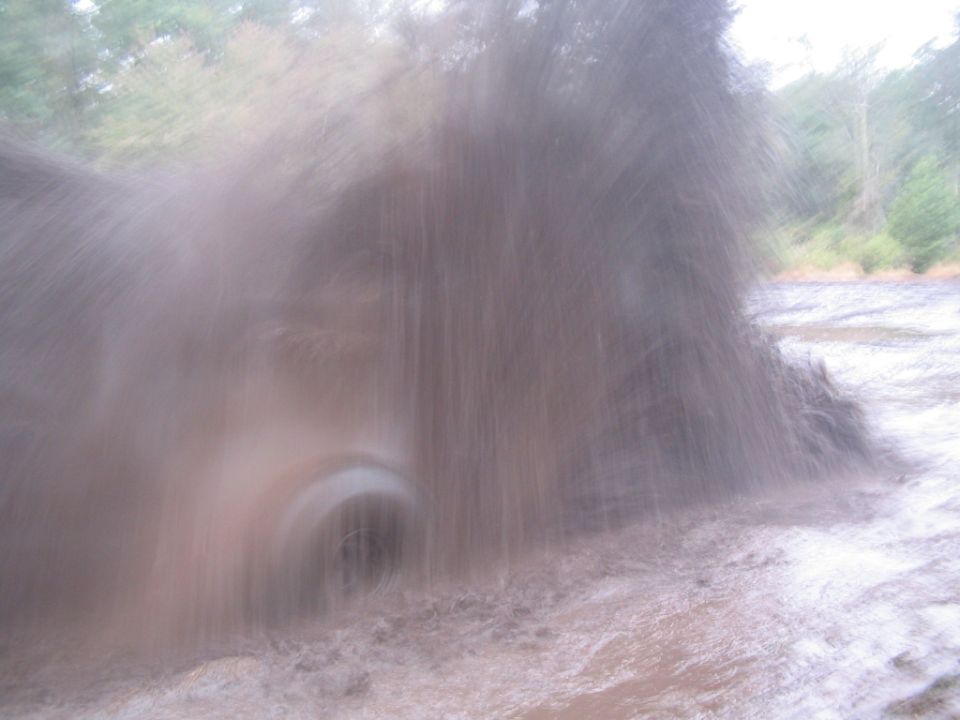 Tire kicking up mud and water, trees in background