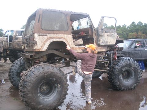 1990 Ford Bronco - A heavily modified off-road vehicle sits in mud, with a person interacting with its side.