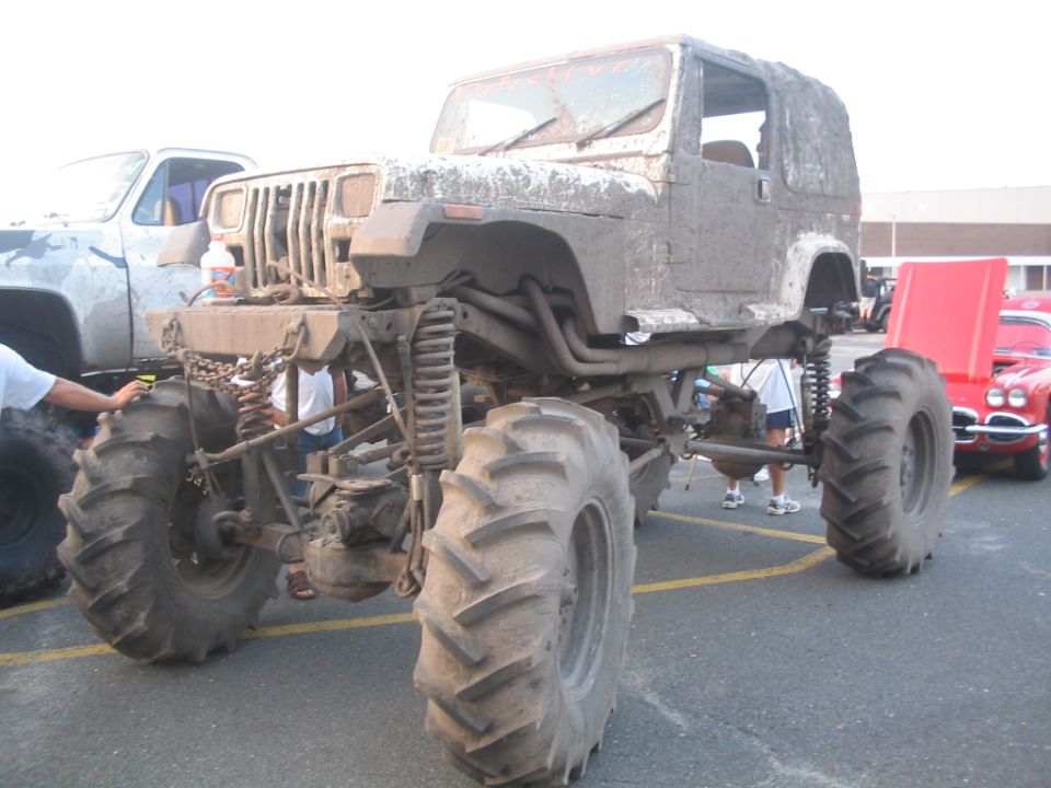 Mud-covered lifted Jeep Wrangler with large tractor tires