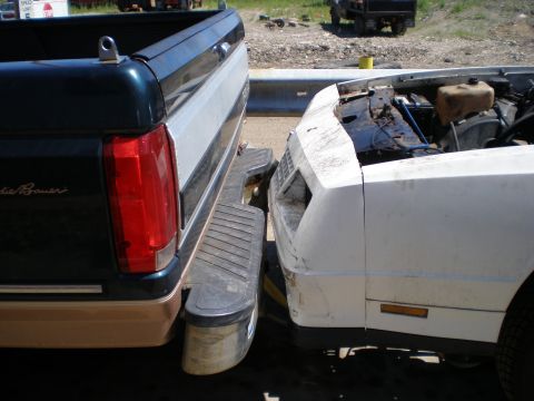 1995 Ford F-150 - Rear view of a dark green and silver pickup truck, possibly a 1995 Ford F-150, parked closely to another vehicle.