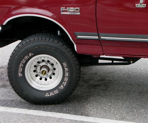 1991 Ford F-150 - Close-up of the front wheel and fender of a red 1991 Ford F-150 Lariat truck.
