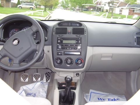1996 Ford F-150 - The interior of a Kia sedan is shown from the driver's perspective, focusing on the dashboard, steering wheel, pedals, and gear shifter.