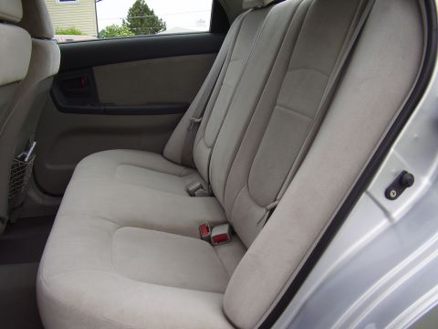 1996 Ford F-150 - The interior of a car shows the rear bench seat and door panel. The seat is upholstered in a light-colored fabric with visible seat belts.