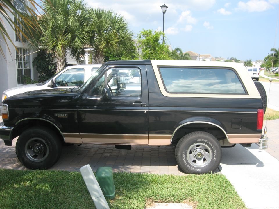 Side view of a black 1995 Ford Bronco with tan trim, parked outdoors.