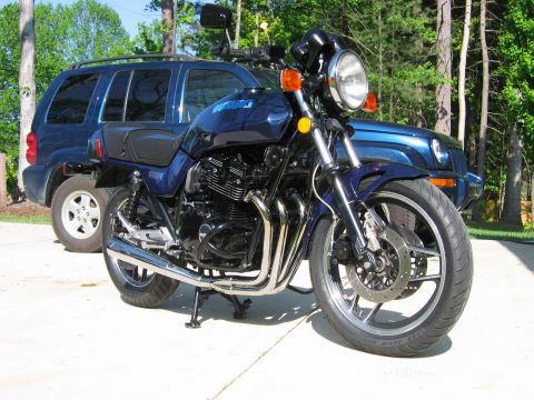 1985 Ford LTD Crown Victoria - Photo of a blue Suzuki standard motorcycle parked on a driveway in front of a Jeep, not a technical document.