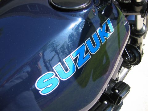 1985 Ford LTD Crown Victoria - Close-up photo of the blue graphic Suzuki logo on a motorcycle fuel tank, not a technical document.