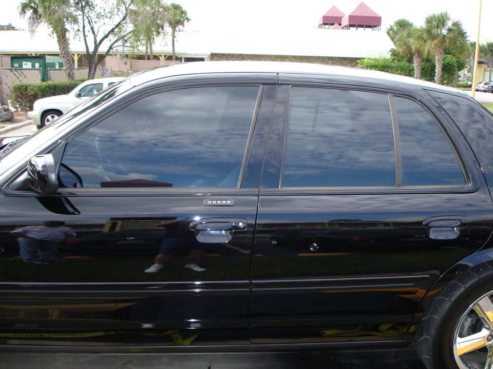 Black 2003 Mercury Marauder side view, tinted windows, chrome rims, reflections.