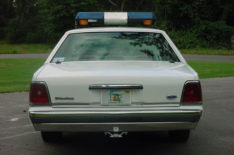1991 Ford Crown Victoria - Rear view of a white 1991 Ford Crown Victoria police car, equipped with a light bar and a license plate.