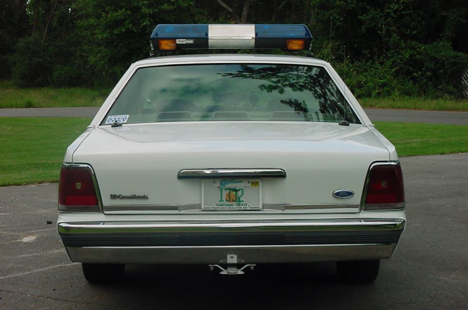 White 1991 Ford Crown Victoria police car rear view with light bar and license plate