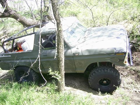 1978 Ford Bronco - This modified SUV, possibly a 1976 Ford Bronco, navigates rough terrain with large off-road tires and custom flame decals.