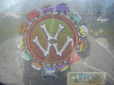 1971 Volkswagen Vanagon - A sticker on a vehicle's window displays cartoon vans and a bone-shaped VW logo.