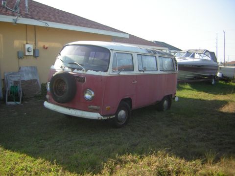 1971 Volkswagen Vanagon - A red and white Volkswagen Type 2 van is parked on a grassy area next to a house, with a boat on a trailer in the background.