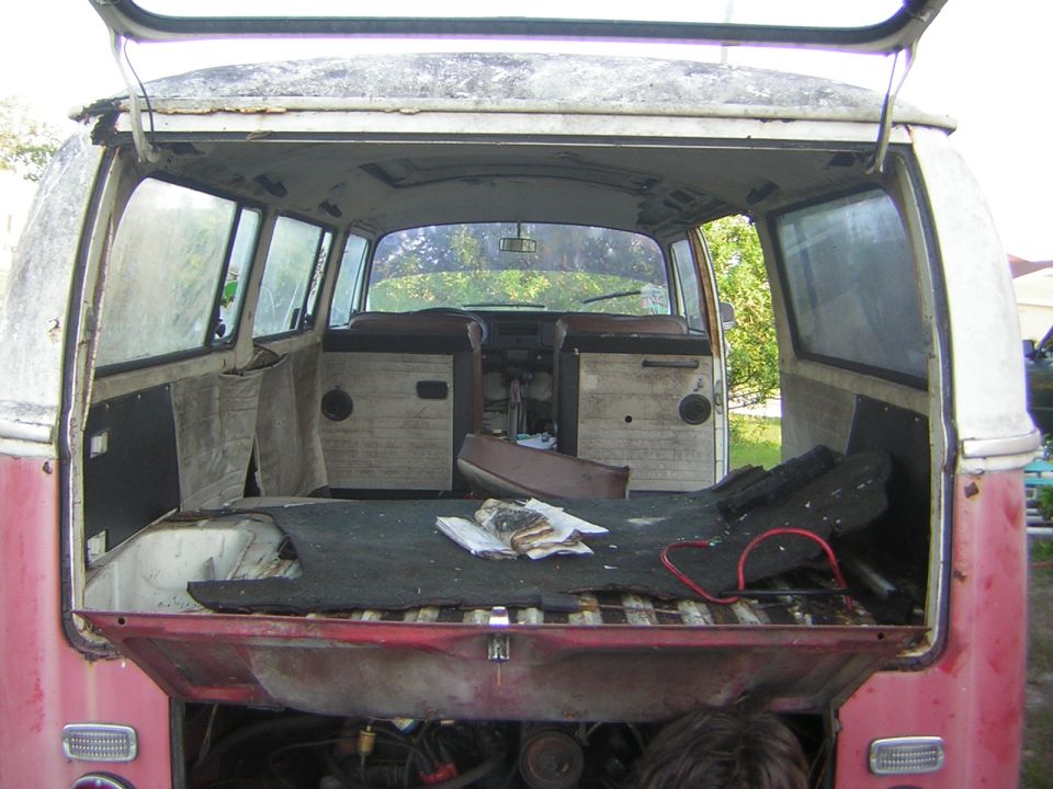Rear interior view of a vintage pink and white Volkswagen bus with tailgate open.