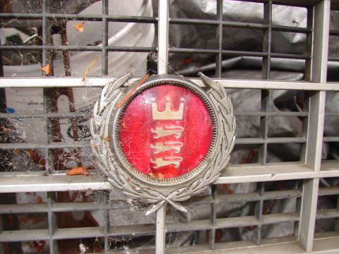 1973 Ford Ranchero - A close-up of a vintage car emblem, featuring a red background with a silver crest depicting three lions, surrounded by a silver laurel wre…