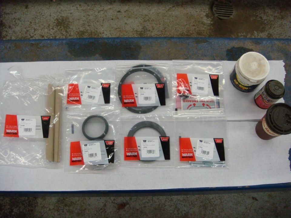 Photo of Warn winch service parts, seals, and lubricant laid out on a bench