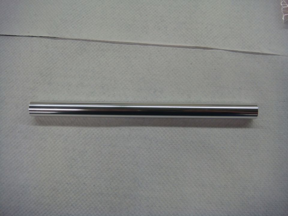 Photo of a polished metal tube or rod on a paper-covered bench