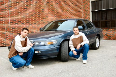 1985 Mercury Grand Marquis - A blue sedan, likely a 1995 Mercury Grand Marquis, is shown with two men crouching in front of it.