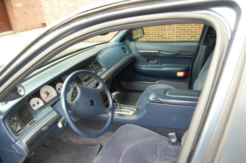 1985 Mercury Grand Marquis - The interior of a car shows a blue dashboard, steering wheel, and seats, with a watermark at the bottom.