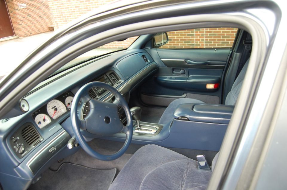 Blue interior of full-size sedan with automatic floor shifter, cloth seats and analog gauges