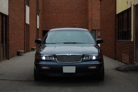 1985 Mercury Grand Marquis - Dark blue sedan parked in an alleyway with brick walls on either side.