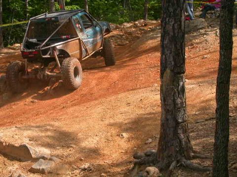 1990 Ford Bronco - Modified off-road vehicle navigates a challenging dirt track during an event.