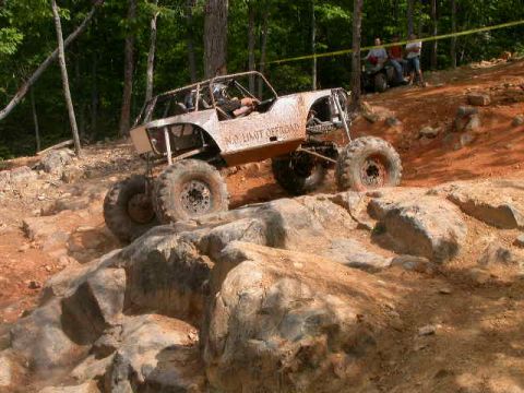 1990 Ford Bronco - A heavily modified off-road buggy navigates a challenging rocky terrain during an event.
