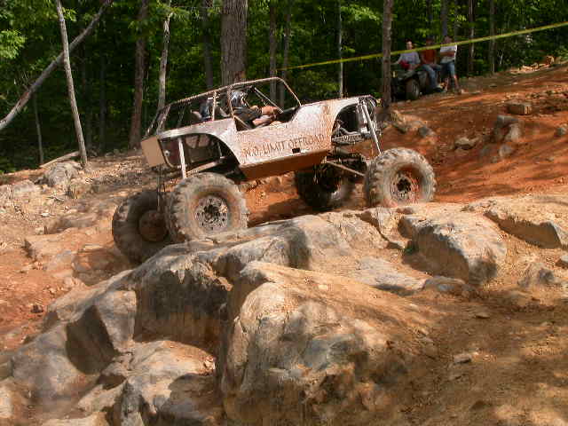 Custom off-road buggy climbing over rocks on a dirt trail. Text on the side reads 'NO LIMIT OFFROAD'