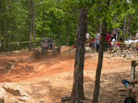 1990 Ford Bronco - An off-road vehicle navigates a dirt track during an event, with spectators gathered nearby.